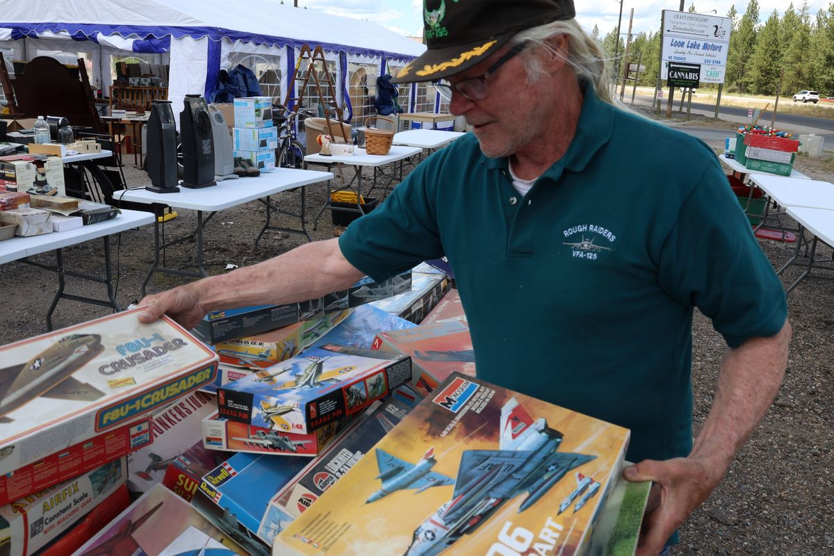 Joe Gately sifts through piles of model airplanes to find the one his brother flew. Gately is selling about 5,000 built and unbuilt airplane models in a three-family estate sale outside the motel he owns on Friday, July 3, 2026, in Loon Lake, Wash.  (Mathew Callaghan / The Spokesman-Review)