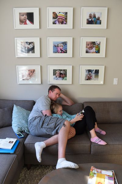 Robbie Parker reads with his daughter, Madeline, 9, beneath a gallery of photographs of their family at their home in Washington state. Robbie and Alissa Parker moved four years ago from Newtown, Conn., for a fresh start for their family after losing their eldest daughter, Emilie, in the Sandy Hook shooting.  (TRIBUNE NEWS SERVICE)