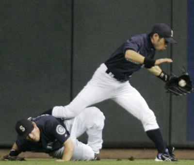 
Seattle's Ichiro Suzuki trips over Chris Snelling to catch a fly ball by Oakland's Frank Thomas. 
 (Associated Press / The Spokesman-Review)