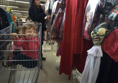 While their babysitter, Trina Lucas, shops for a Halloween costume, 2-year-old twins Elsie, front, and Nyla Hess keep a watchful eye out for ghosts and goblins haunting Value Village in Spokane on Tuesday.  (Colin Mulvany / The Spokesman-Review)