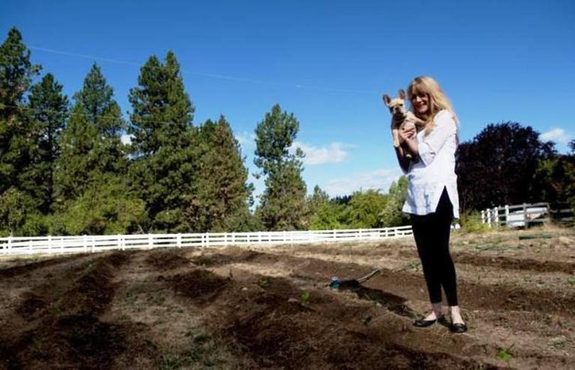 Josephie Dean Jackson holds Frank, a French bulldog, in her freshly planted tea garden Thursday. (Kathy Plonka / Spokesman-Review)