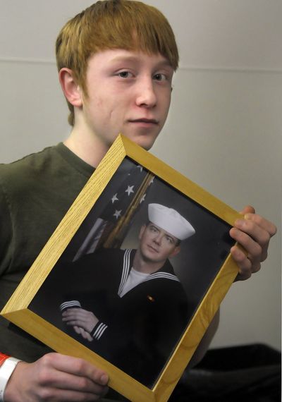 Cody Young holds a photo of his father who is shown dressed in his Navy uniform.  (Christopher Anderson / The Spokesman-Review)