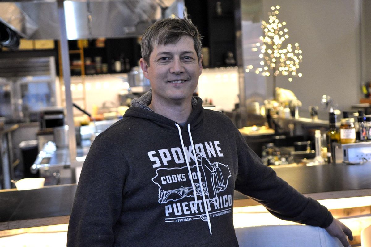 Chef Jeremy Hansen models a Spokane Cooks for Puerto Rico sweatshirt in the dining room of Inland Pacific Kitchen, one of his downtown Spokane restaurants. Proceeds will go toward meals for victims of Hurricane Maria. Christmas Day is the last day to order apparel for the fundraiser. (Adriana Janovich / The Spokesman-Review)
