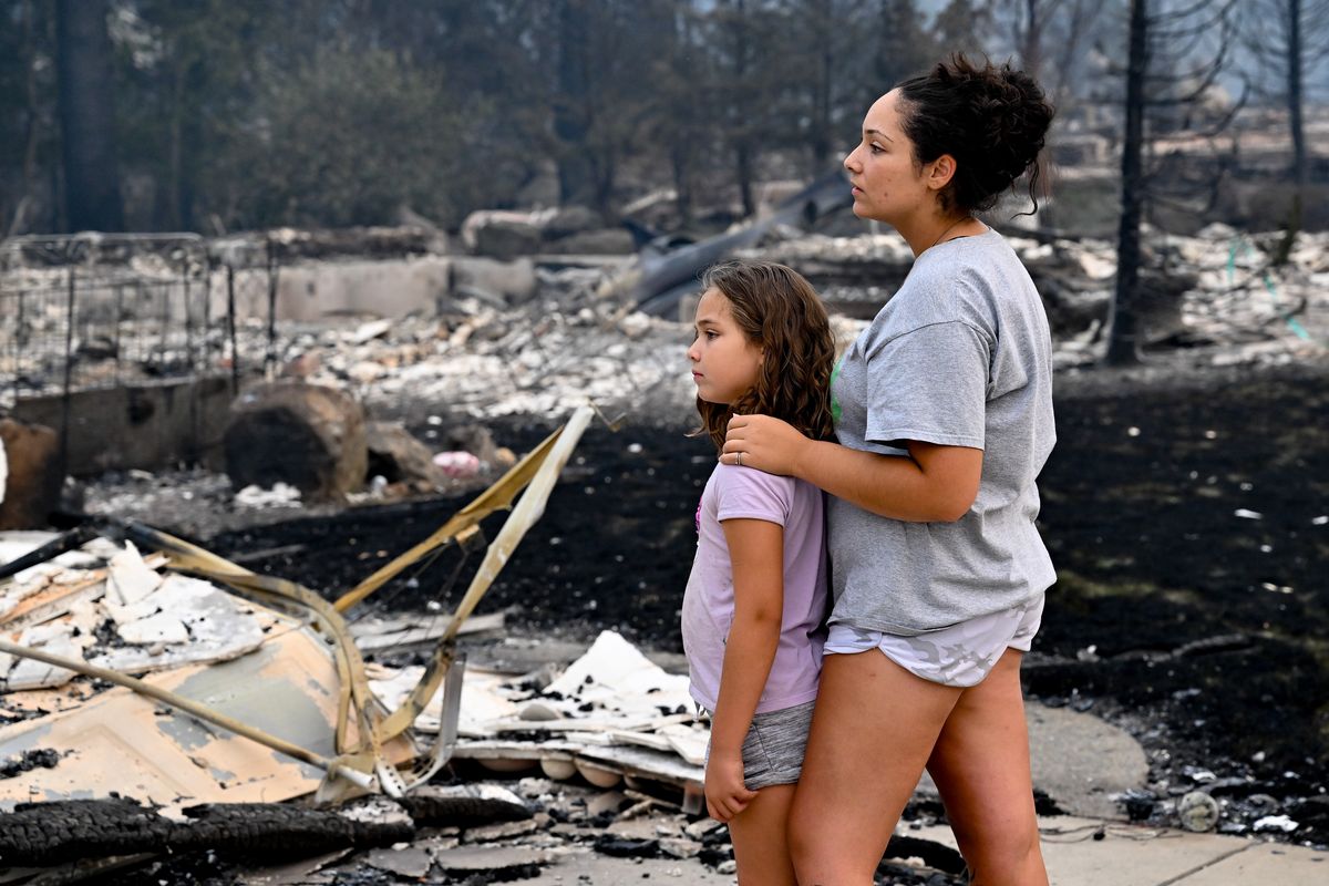Jazmine Talley holds her daughter Marley, 7, as they stand at the ruins of her parents’ Evergreen Drive home on Saturday, Aug. 19, 2023, after it was destroyed, Friday, by the Gray Fire in Medical Lake, Wash.  (Tyler Tjomsland/The Spokesman-Review)