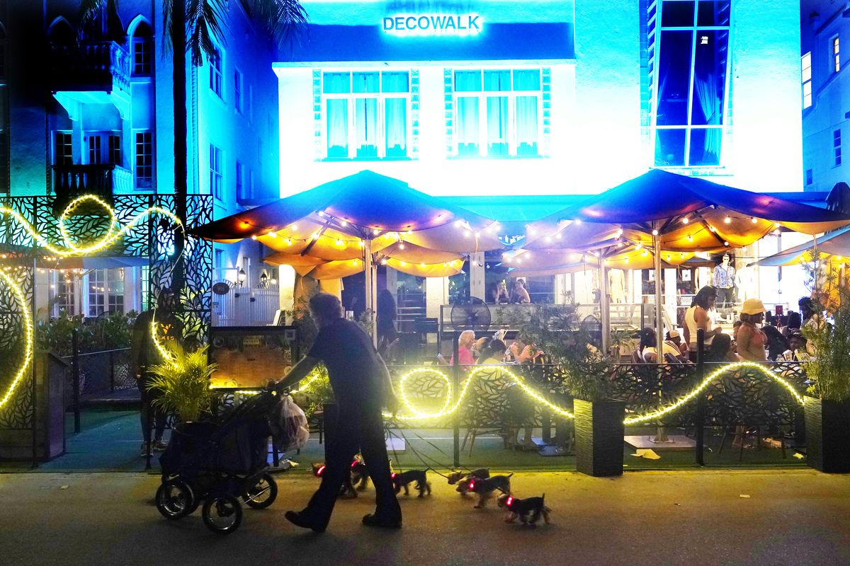 A man walks his dogs Sept. 15 on Ocean Drive in Miami Beach, Fla. The 10-block area of South Beach has been closed to traffic since the pandemic began, making it difficult for hotel guests and restaurant patrons to park their cars.  (Marta Lavandier)
