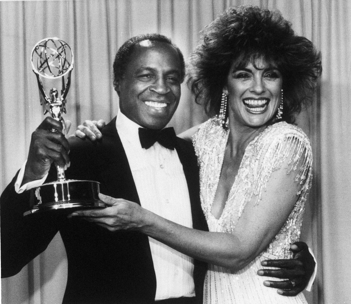 FILE - In this Sept. 22, 1985 file photo, actor Robert Guillaume, star of "Benson", gets a hug from Linda Gray of "Dallas" who presented him with the Emmy for outstanding lead actor in a comedy series, in Pasadena, Calif.  Guillaume, who won Emmy Awards for his roles on Soap and Benson, died Tuesday, Oct. 24, 2017 in Los Angeles at age 89. Guillaumes widow Donna Brown Guillaume says he had been battling prostate cancer. (AP Photo/File) ORG XMIT: NYET232 (AP)