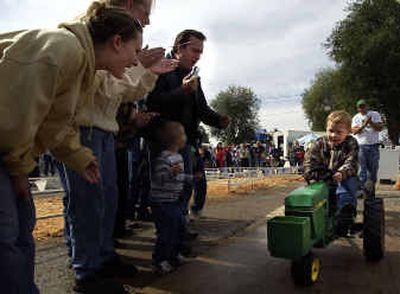 
Cameron Hughes, 5, from Missoula, pushes for the finish line as his family cheers him on in the fourth round of the Kids Tractor Pull competition Sunday on the last day of the fair. Hughes was the only contestant to make it into the fourth round and met the challenge of 100 pounds. 
 (Liz Kishimoto / The Spokesman-Review)