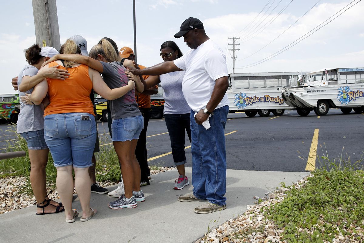 People pray outside Ride the Ducks, an amphibious tour operator involved in a boating accident on Table Rock Lake, Friday, July 20, 2018 in Branson, Mo. (Charlie Riedel / AP)