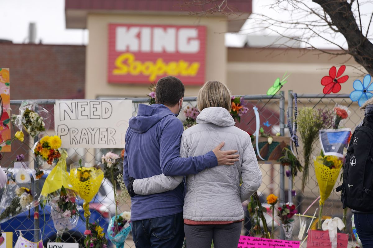 FILE - In this March 26, 2021, file photo, mourners walk the temporary fence line outside the parking lot of a King Soopers grocery store, the site of a mass shooting in Boulder, Colo. Colorado prosecutors have filed over 40 more felony charges against the man charged with killing 10 people at the Boulder supermarket last month — including allegations he used a large capacity magazine that had been banned by state lawmakers in 2013 in response to mass shootings.  (David Zalubowski)