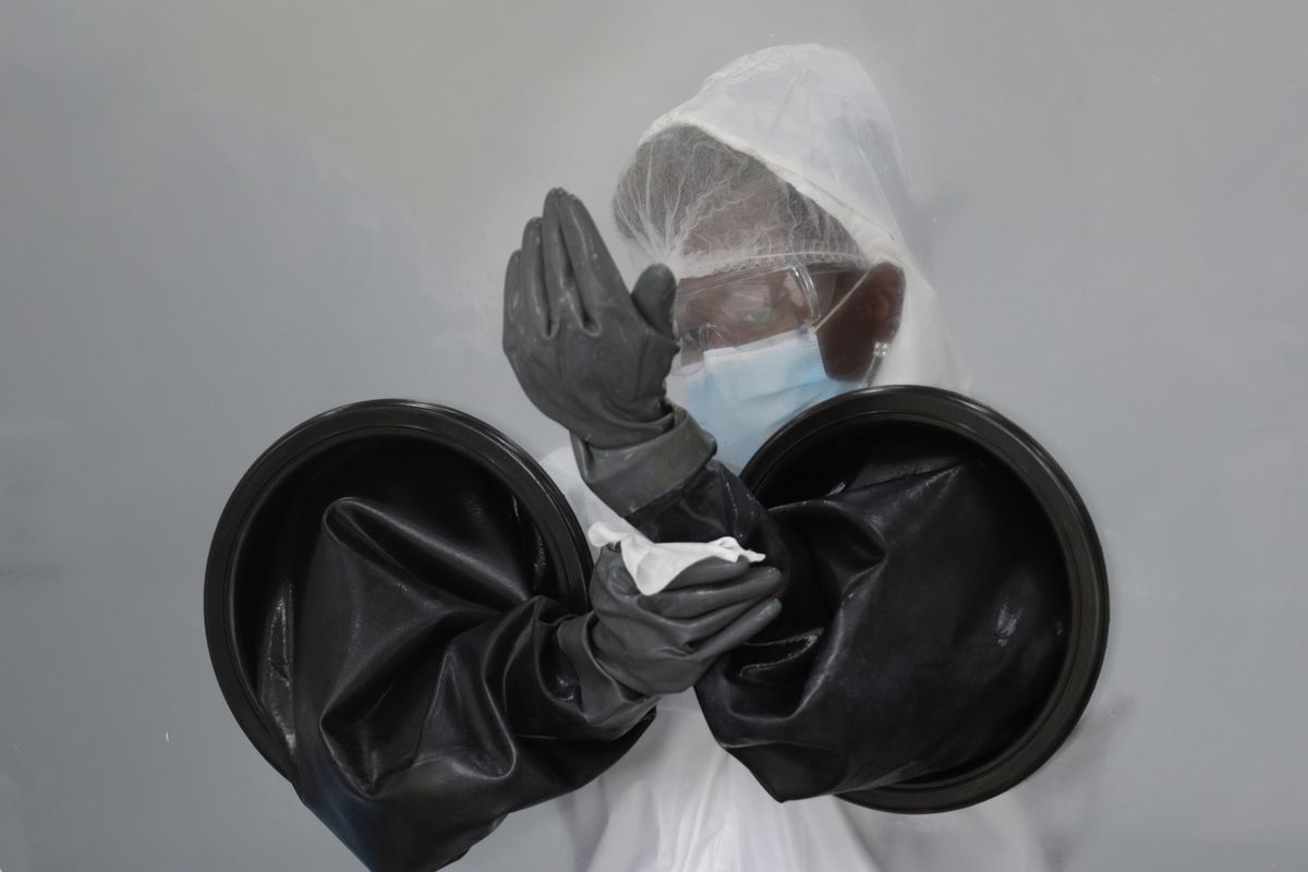 FILE - In this July 17, 2020, file photo, a health care worker sanitizes her equipment while working at a walk-up COVID-19 testing site during the coronavirus pandemic in Miami Beach, Fla. As the world races to find a vaccine and a cure for COVID-19, there is seemingly no antidote in sight to the burgeoning outbreak of coronavirus conspiracy theories, hoaxes, anti-mask myths and sham treatments.  (Lynne Sladky)