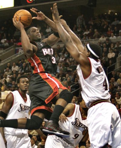 
Miami's Dwyane Wade soars over Philadelphia's Chris Webber for two of his 32 points on Friday.
 (Associated Press / The Spokesman-Review)