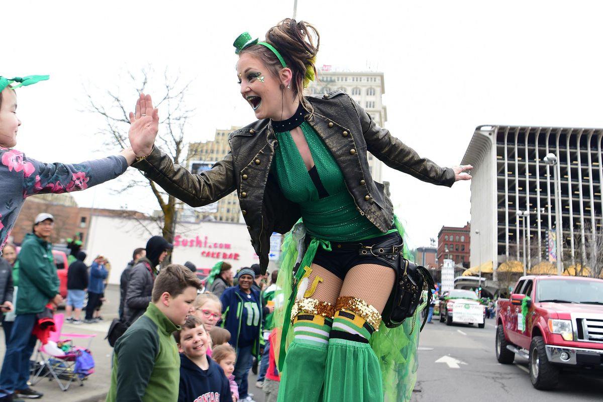 Stilt walker Ashley Werner leans down to high five children along the parade route in the annual St. Patrick’s Day Parade, Saturday, Mar. 17, 2018, in downtown Spokane. (Jesse Tinsley / The Spokesman-Review)