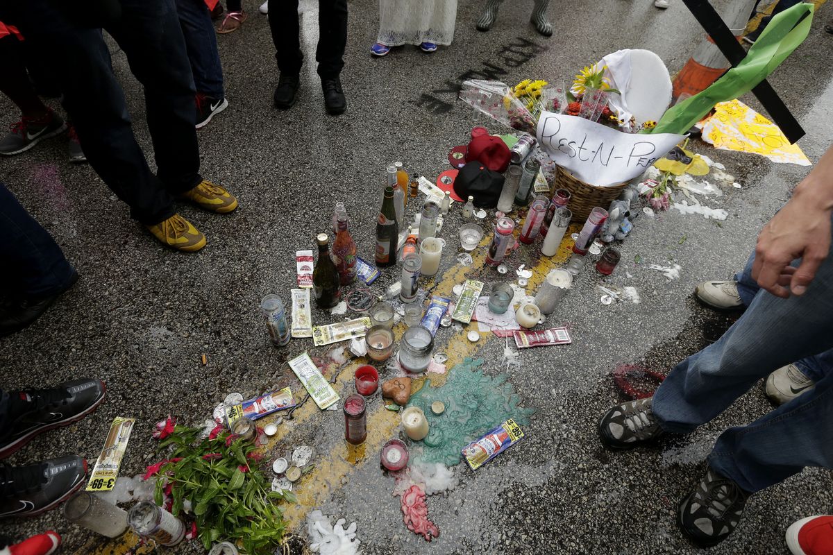 People gather around a makeshift memorial for Michael Brown on Saturday, Aug. 16, 2014, located at the site where Brown was shot by police a week ago in Ferguson, Mo. Brown