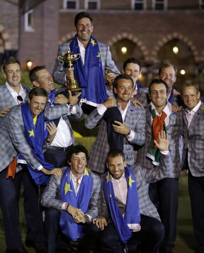 The European team poses with the Ryder Cup trophy after coming from way behind to win by a point in Medinah, Ill. (Associated Press)