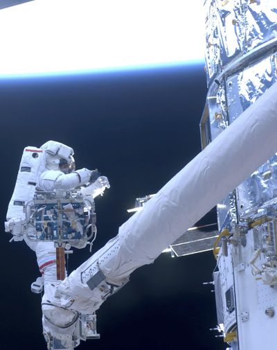In this photo provided by NASA, astronaut John Grunsfeld, STS-125 mission specialist, positioned on a foot restraint on the end of Atlantis’ remote manipulator system (RMS), participates in the mission's fifth and final session of extravehicular activity (EVA) to refurbish and upgrade the Hubble Space Telescope on Monday May 18, 2009. (Associated Press)
