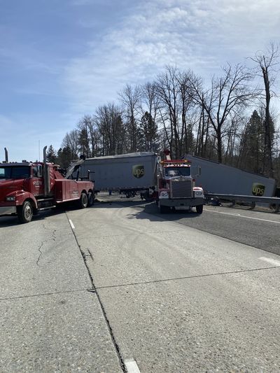 Tow trucks work to clear a semitruck from a ditch Thursday on Interstate 90 near Cle Elum, Wash. The semi crossed the median and struck a Kia Optima, killing three people and injuring two others inside the Kia, according to the Washington State Patrol.  (Courtesy of Washington State Patrol)