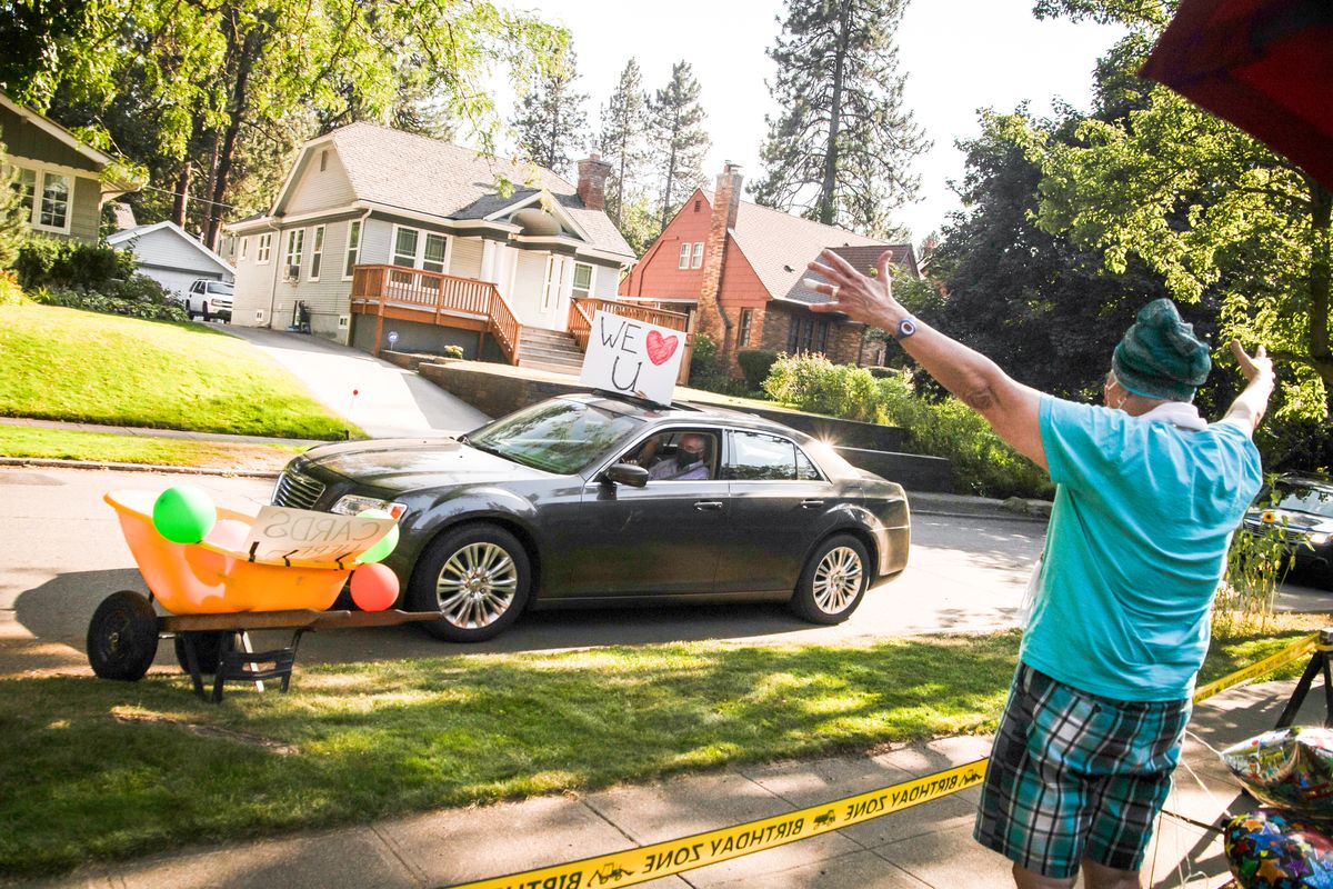 Chris Henze gives a "covid hug" to guests during her surprise birthday party parade on July 28, 2020 in Spokane, Wash. Chris is undergoing chemotherapy for ovarian cancer and Catherine Henze, her wife, invited approximately 100 friends, family members and neighbors for a socially distant celebration. (Libby Kamrowski/The Spokesman-Review)