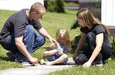 Jade Airheart, center, checks to see if she has sidewalk chalk on her foot while playing with her parents, Luke and Cindy Airheart, outside their home in Moscow on Sunday. Luke Airheart, a member of the Idaho National Guard, will be deployed on June 28.
(Associated Press / The Spokesman-Review)