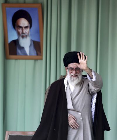 In this photo released by his office, Iranian Supreme Leader Ayatollah Ali Khamenei waves under a portrait of Ayatollah Khomeini in Kermanshah on Wednesday. (Associated Press)