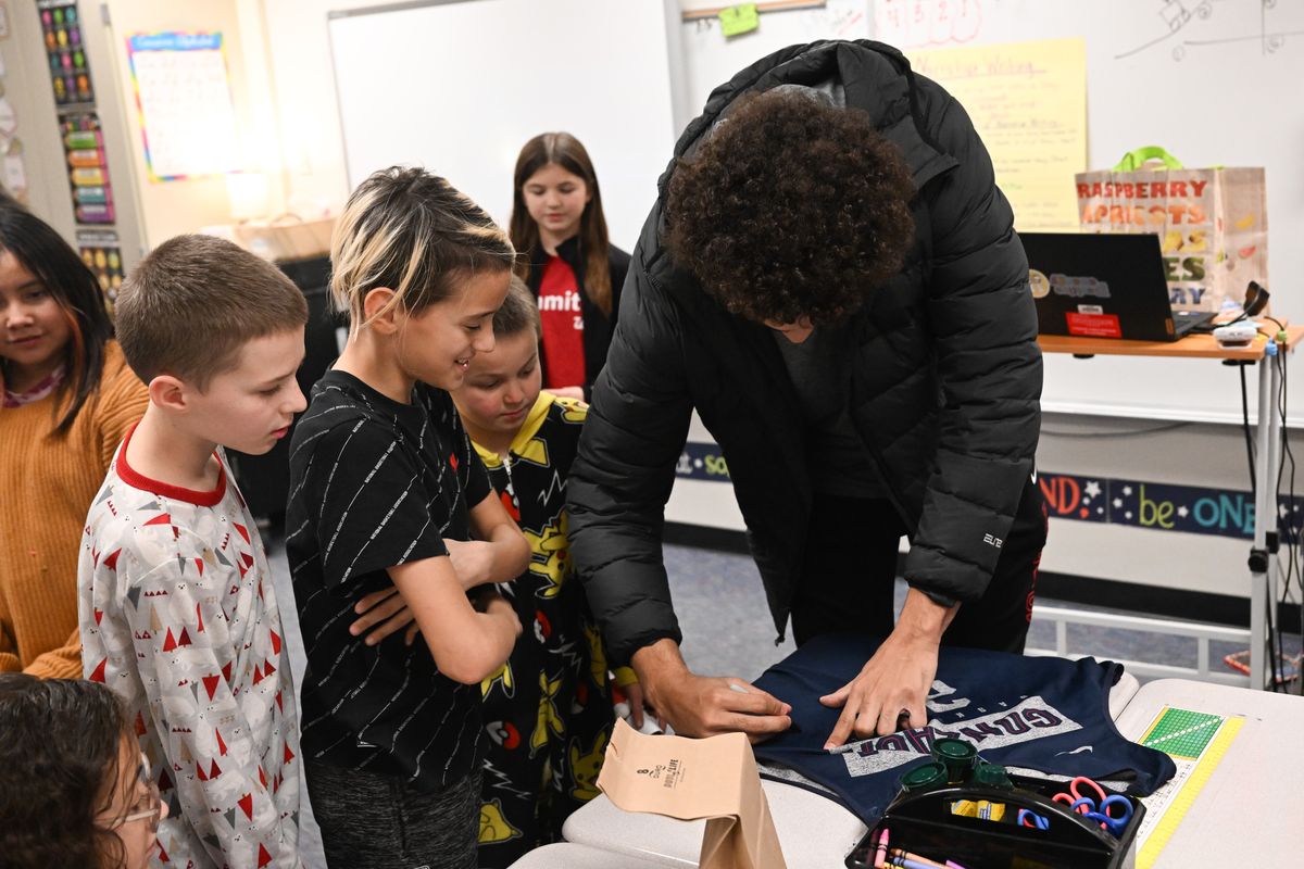 5th grader Ezekiel Avila, third from left, reacts as Gonzaga’s Anton Watson signs one of the practice jerseys from his freshman year that he gave Avila on Friday, Dec. 22, 2023, at Willard Elementary in Spokane, Wash. When Avila asked for a basketball for Christmas, Willard staff and Chauncy Welliver contacted Watson who brought a ball and one of his jerseys for Avila.  (Tyler Tjomsland/The Spokesman-Review)