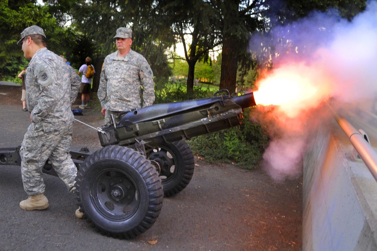 Army National Guard Spc. Gerardo Najera, left and Spc. Ben Miller fire off a 75mm howitzer to signal the start of the Spokane Lilac Festival
