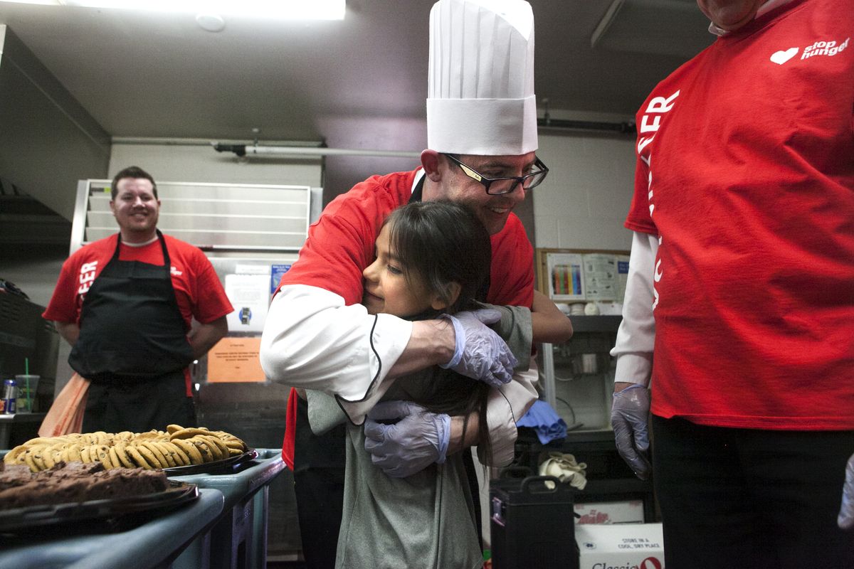 Gonzaga chef manager Tompall Nichols is hugged by Michael Fox, 8, after preparing a meal of lasagna for Fox’s family and others during a free community dinner Tuesday at the Salvation Army Community Center in Spokane. Fox’s mother, Chana, said her boys wanted to hug the chef after finishing their meal, so she sent them to the kitchen to look for him. (Tyler Tjomsland)