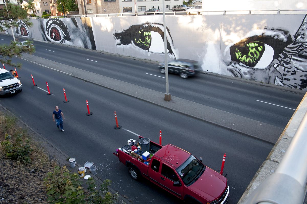 Artist Todd Benson walks along his work-site where he has painted murals on Monday, July 25, 2016, on Maple Street in Spokane, Wash. Benson is painting the mural at the northeast end of the Maple Street Bridge to celebrate Spokane