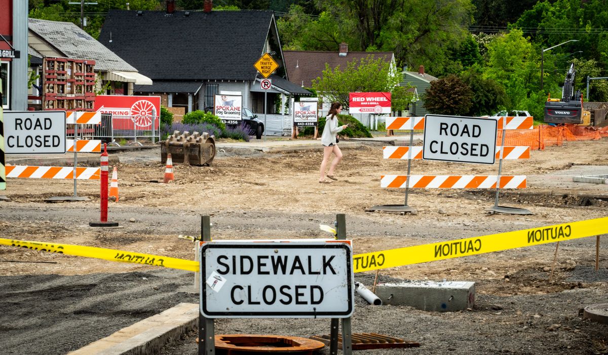 A pedestrian makes her way through road construction at Fifth Avenue and Thor Street in this June photo. The lead contractor on the project has complained to the city that vandalism and other criminal activity is slowing progress on the rebuild.  (COLIN MULVANY/THE SPOKESMAN-REVI)