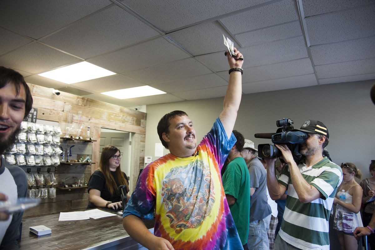 Mike Boyer turns to the crowd waiting outside and shows off 4 grams of pot he bought as the first in line at Spokane Green Leaf on Tuesday. (Dan Pelle)