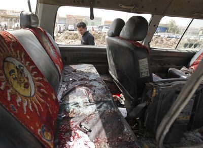 A minibus driver  surveys the damage to his vehicle after a roadside bombing in Baghdad, Iraq, on Monday.  (Associated Press / The Spokesman-Review)