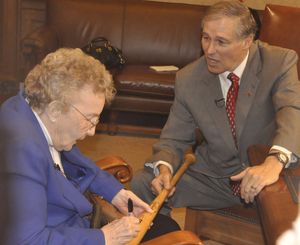 OLYMPIA -- Dorothy Roth, who played in the National Girls Baseball League in 1945, autographs a bat for Gov. Jay Inslee during a ceremony at the state Capitol. (Jim Camden)