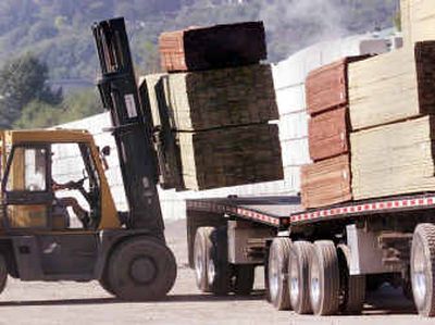 
A forklift operator unloads softwood lumber at Pacific Terminals in north Vancouver, Canada, last year. The Commerce Department on Tuesday cut punitive tariffs on imports of Canadian softwood lumber from an average of 27.2 percent to 21.2 percent. 
 (Canadian Press / The Spokesman-Review)
