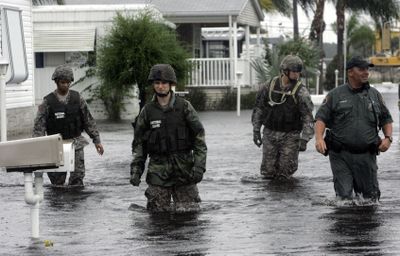 National Guard troops and local law enforcement officers wade through water in Melbourne, Fla., on Thursday, helping residents evacuate from the flooding caused by Tropical Storm Fay.  (Associated Press / The Spokesman-Review)