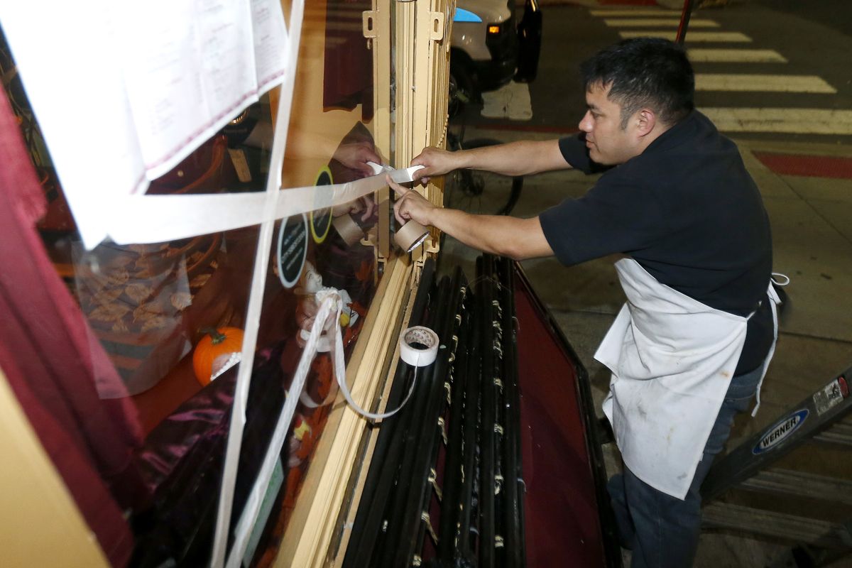 Oswaldo Falleres puts tape on the window of a restaurant in preparation for the arrival of superstorm Sandy, Sunday, Oct. 28, 2012, in Hoboken, N.J. Tens of thousands of people were ordered to evacuate coastal areas Sunday as big cities and small towns across the U.S. Northeast braced for the onslaught of a superstorm threatening some 60 million people along the most heavily populated corridor in the nation. (Julio Cortez / Associated Press)