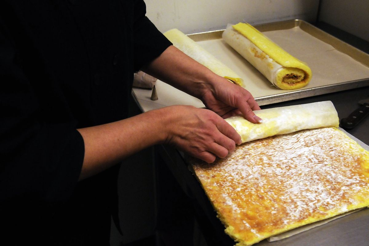 Eva Roberts, owner of Just American Desserts in the Spokane Valley, rolls the pastry for a traditional yule log. The first step is to roll baked sponge cake on parchment paper sprinkled with confectioners’ sugar. The sugar keeps the cake from sticking to the parchment. (J. Bart Rayniak / The Spokesman-Review)
