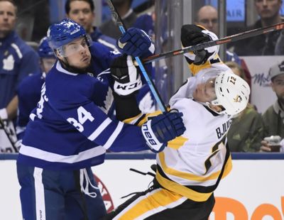 Toronto Maple Leafs center Auston Matthews (34) and Pittsburgh Penguins center Nick Bjugstad (27) battle during the second period of an NHL hockey game in Toronto on Saturday, Feb. 2, 2019. (Nathan Denette / Canadian Press via AP)
