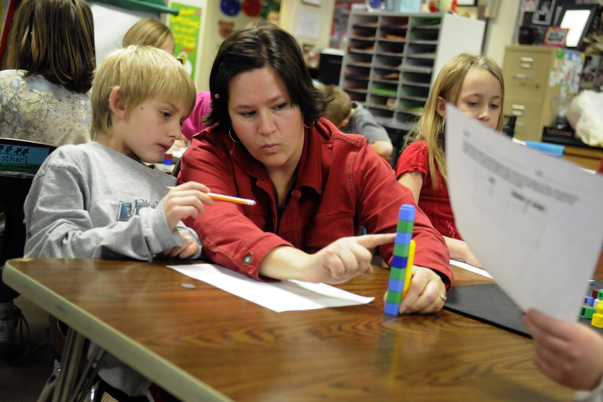 Second-grade teacher Natalie Andres helps Keaton Lusk during a problem-solving exercise at Orchard Center Elementary School on Wednesday. Andres recently received national board certification,  a designation that will allow her to teach in any state. (J. Bart Rayniak)