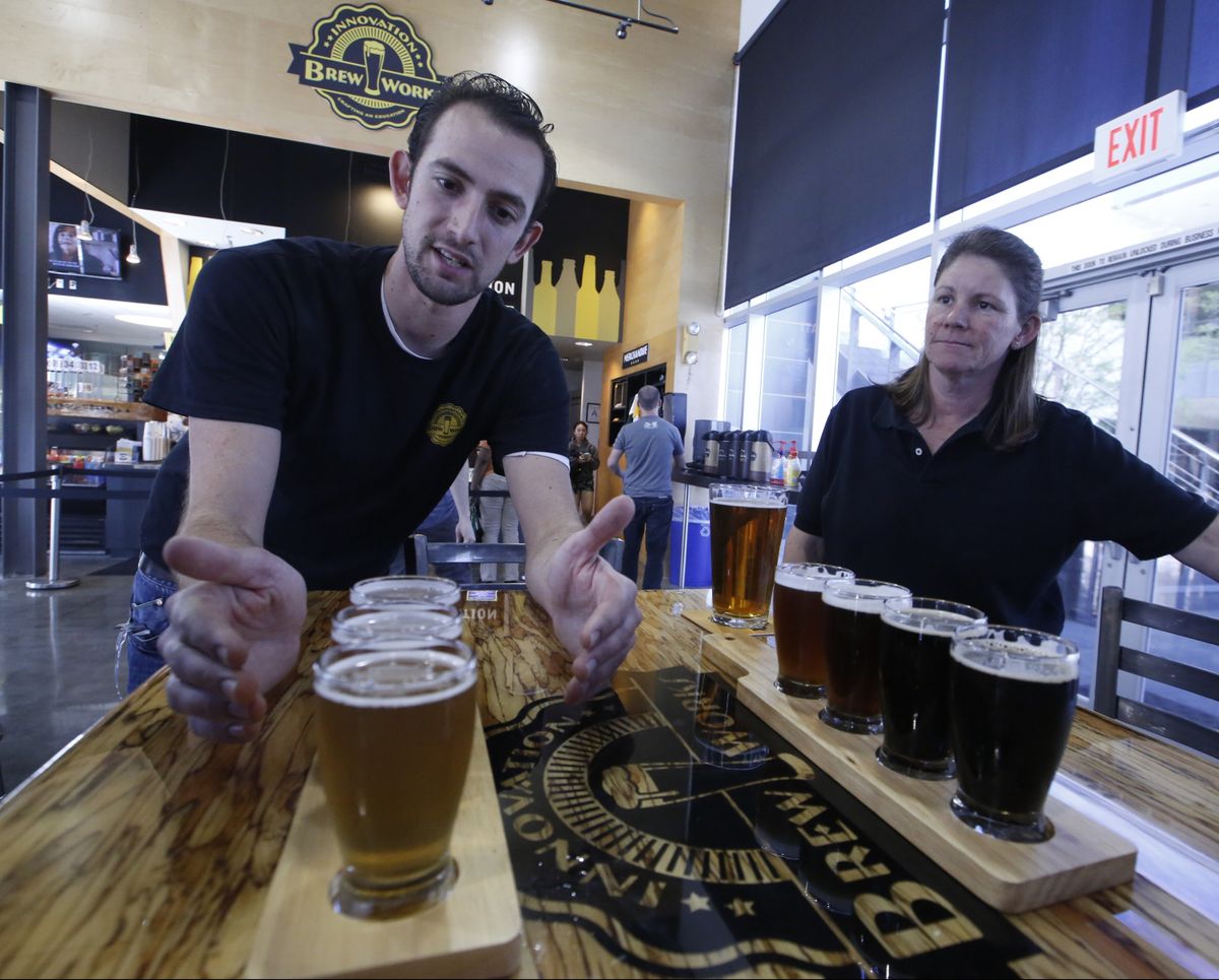 Koby Harris, brewery production manager, left, and Sandra Cain, assistant director of retail operations, present their freshly brewed beers at Innovation Brew Works. (Associated Press)