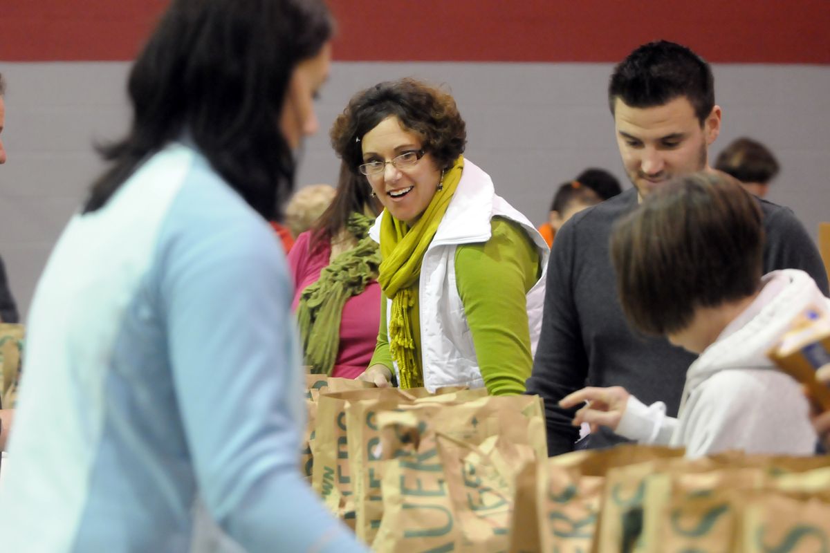 Volunteer Susan Rauer, center, helps move groceries and turkeys down the line the Salvation Army Center