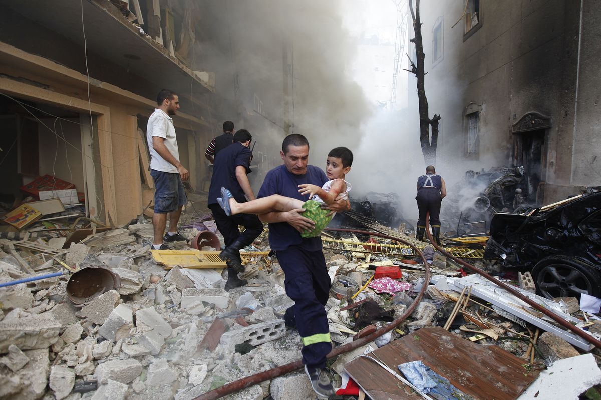 An injured boy is carried from the scene of a car-bomb explosion in Beirut on Friday. (Associated Press)
