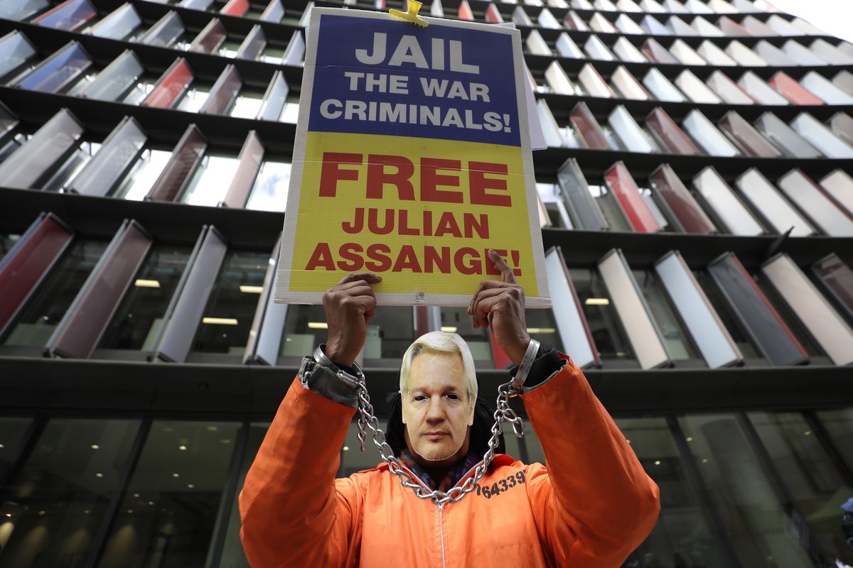 A demonstrator holds a banner and wears a Julian Assange mask opposite the Old Bailey in London, Thursday, Oct. 1, 2020, as the Julian Assange extradition hearing to the US continues.  (Kirsty Wigglesworth)