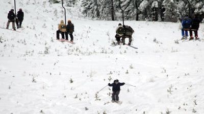 
A skier takes a small jump while others ride the lifts up the front side of Lookout Pass Ski Area on the Idaho-Montana border Thursday, the resort's first day of operation for the season. Despite minimal coverage, a few hundred skiers and snowboarders showed up to the resort. 
 (Photos by JESSE TINSLEY / The Spokesman-Review)