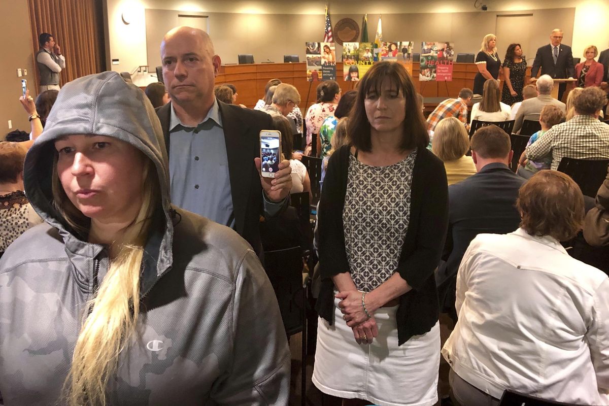 Anti-vaccination protestors Christie Nadzieja, front, Bob Runnells, back left, and Katie Bauer, back right, all of Vancouver, Washington, stand up and turn their backs on Gov. Jay Inslee on Friday, May 10, 2019, in Vancouver, Wash., as he signs a bill into law that eliminates personal belief and philosophical exemptions for the measles mumps and rubella vaccine for children who wish to attend school or day care. (Gillian Flaccus / Associated Press)