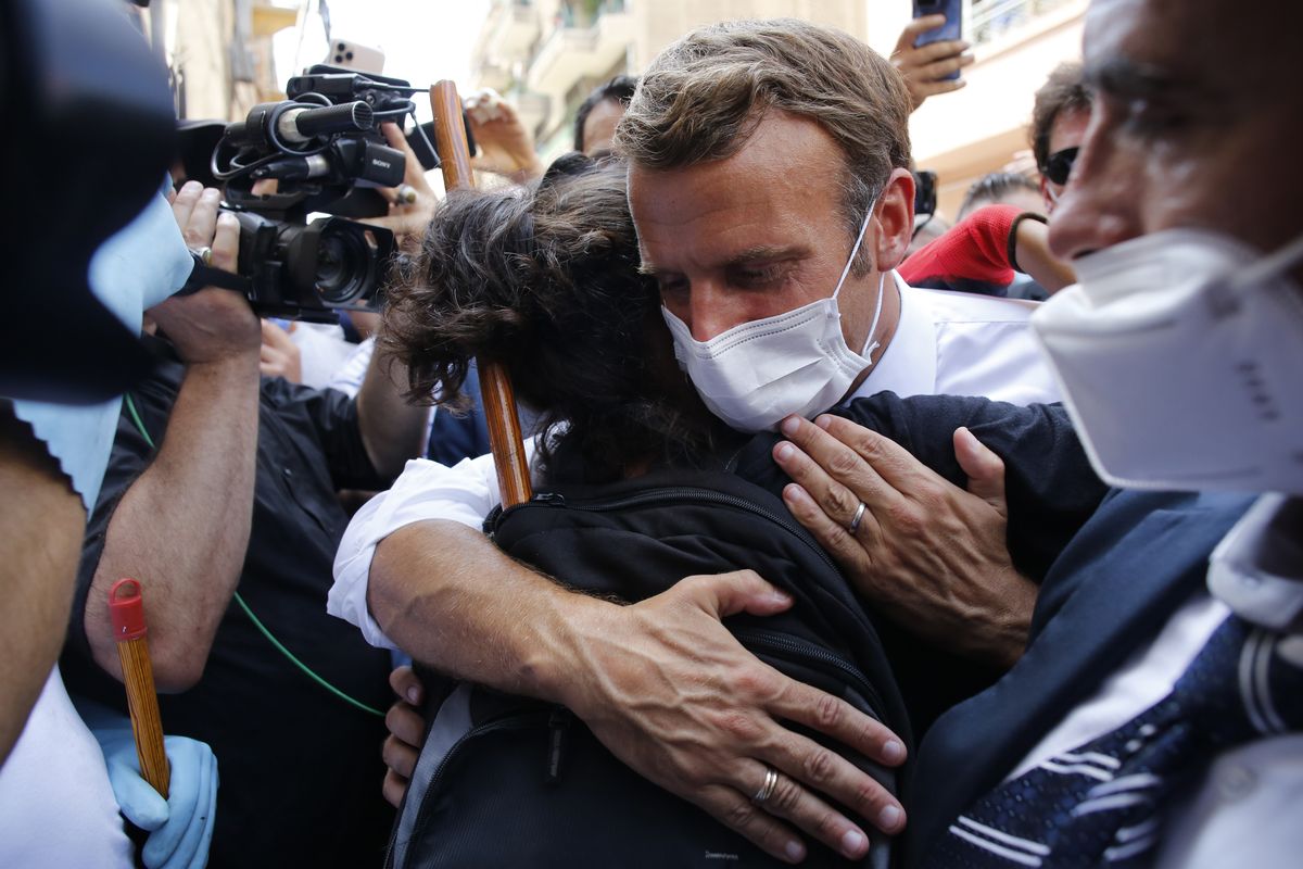 French President Emmanuel Macron hugs a resident as he visits a devastated street of Beirut, Lebanon, Thursday Aug.6, 2020. French President Emmanuel Macron has arrived in Beirut to offer French support to Lebanon after the deadly port blast. (Thibault Camus)
