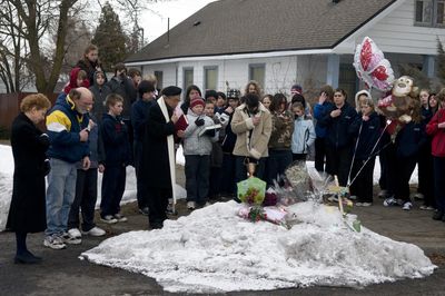 The Rev.  Joe Hien, of St. Anthony’s Catholic Church, leads a prayer with Trinity Catholic School students Thursday at the intersection of Cedar Street and Carlisle Avenue, where police say Susette Werner was struck and killed by a  driver Sunday morning.  (Colin Mulvany / The Spokesman-Review)