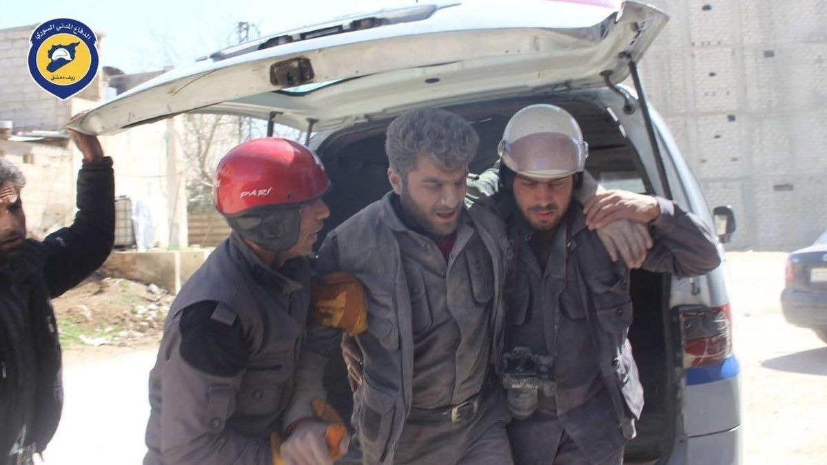 Civil Defense workers help their teammate after airstrikes hit a main street, killing many people, activists said, in the Damascus suburb of Hamouriyeh, Syria, Saturday. The airstrikes, of which some activists said included Russian air raids, concentrated on the rebel-held northwestern province of Idlib, the central province of Hama and suburbs of the capital Damascus that has come under attack by insurgent groups over the past week. (Uncredited / Syrian Civil Defense White Helmets via Associated Press)