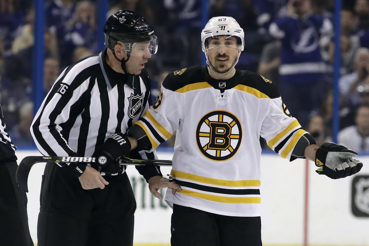 Boston Bruins left wing Brad Marchand (63) is escorted off the ice by linesman Michel Cormier (76) after taking a penalty against the Tampa Bay Lightning during the first period of Game 5 of an NHL second-round hockey playoff series Sunday, May 6, 2018, in Tampa, Fla. (Chris O’Meara / Associated Press)