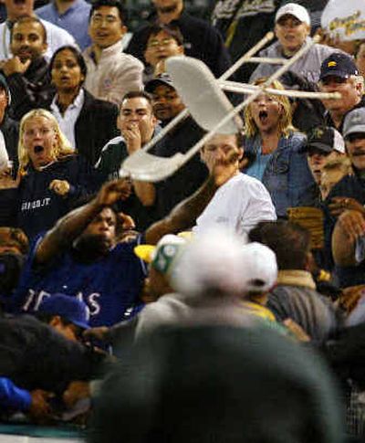 Rangers reliever Frank Francisco, bottom left, hurls a ballboy's chair into the crowd of A's fans on Monday.
(Associated Press / The Spokesman-Review)