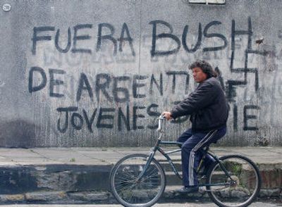 
A man rides his bike past graffiti which reads 