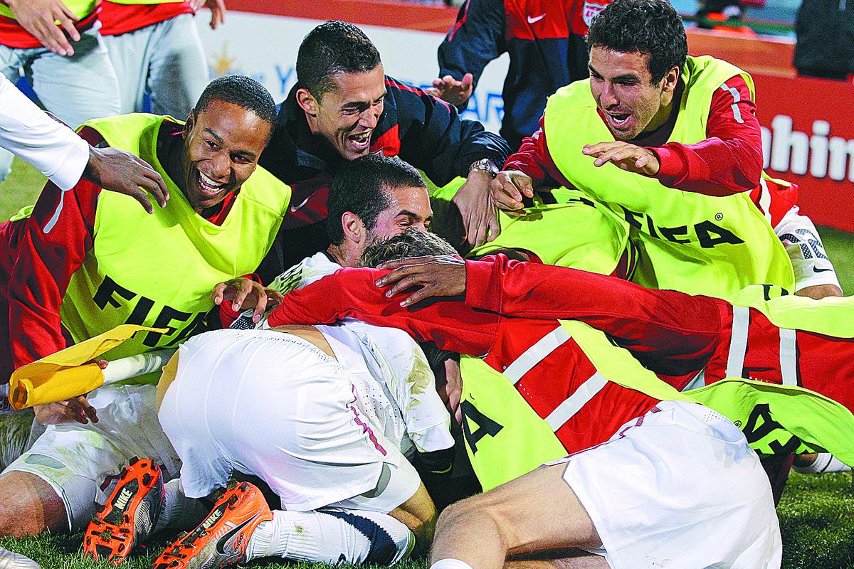 Teammates pile on Landon Donovan after his goal in stoppage time gave United States a 1-0 win over Algeria and Pool C title. (Associated Press)